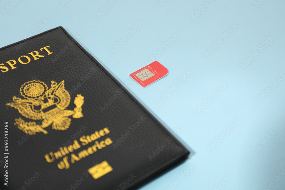 Modern SIM card and passport on light blue background, closeup Modern SIM card and passport on light blue background, closeup