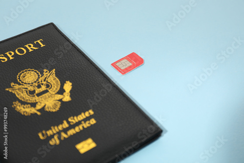 Modern SIM card and passport on light blue background, closeup photo