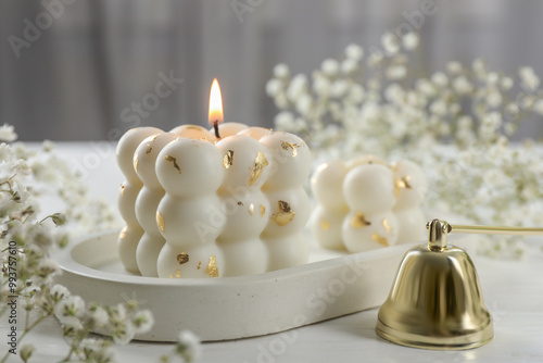 Stylish bubble candles, snuffer and gypsophila flowers on white wooden table, closeup photo