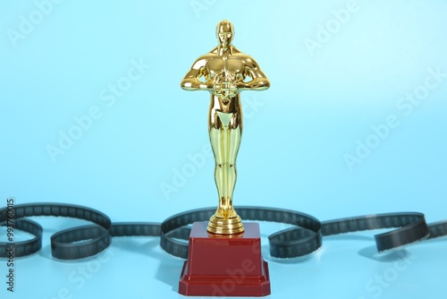 Golden Oscar award and film reel on light blue background