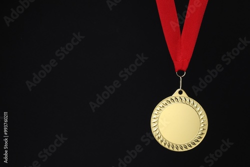 Golden medal with red ribbon on black background, space for text photo