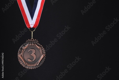 Bronze medal with striped ribbon on black background, space for text