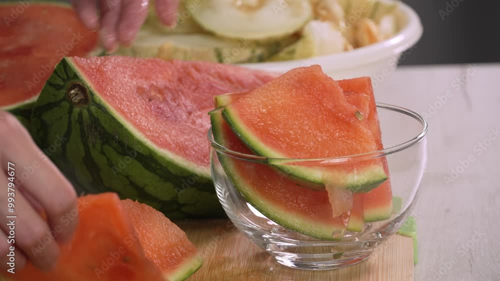 Hands of young woman european transferring sliced watermelon pieces into a bowl, left side view close up. Healthy lifestyle concept, raw food diet, cooking at home, refreshing Hands of young woman european transferring sliced watermelon pieces into a bowl, left side view close up. Healthy lifestyle concept, raw food diet, cooking at home, refreshing