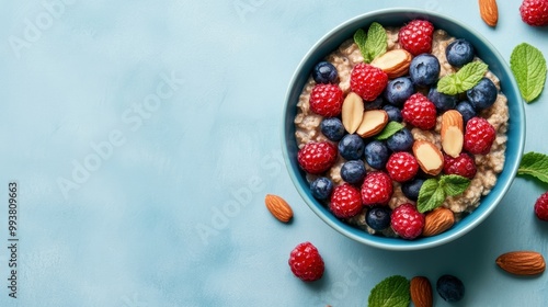 Wallpaper Mural Delicious bowl of oatmeal topped with fresh blueberries, raspberries, almonds, and mint leaves on a light blue background. Torontodigital.ca