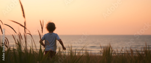 Young Boy Walking Towards the Ocean at Sunset.
