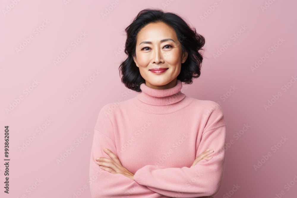 Portrait of a content asian woman in her 50s wearing a classic turtleneck sweater while standing against pastel or soft colors background Portrait of a content asian woman in her 50s wearing a classic turtleneck sweater while standing against pastel or soft colors background
