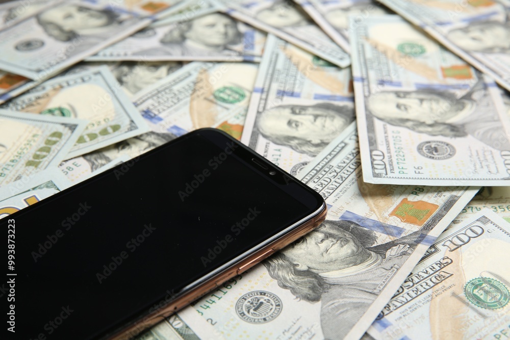 Modern smartphone on dollar bills, closeup view Modern smartphone on dollar bills, closeup view