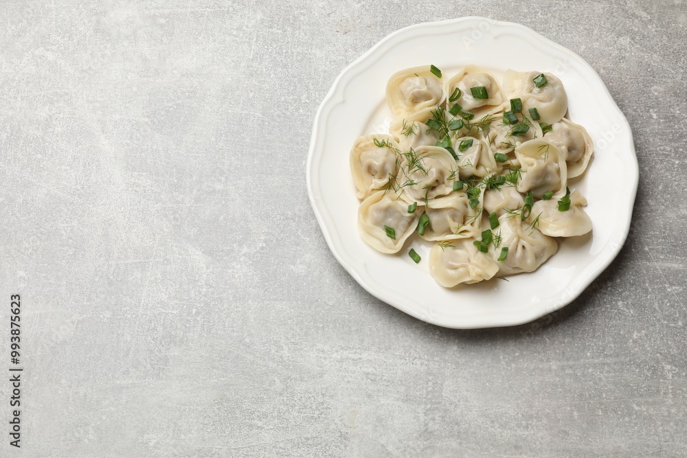 Delicious pelmeni with green onion and dill on grey textured table, top view. Space for text Delicious pelmeni with green onion and dill on grey textured table, top view. Space for text