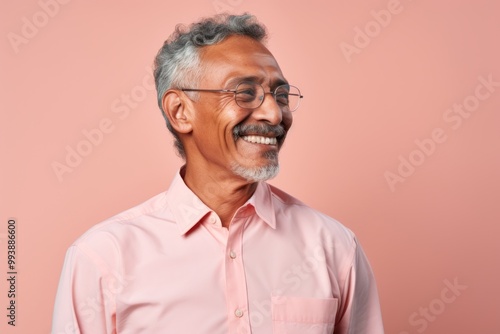 Portrait of a satisfied indian man in his 60s sporting a technical climbing shirt over pastel or soft colors background