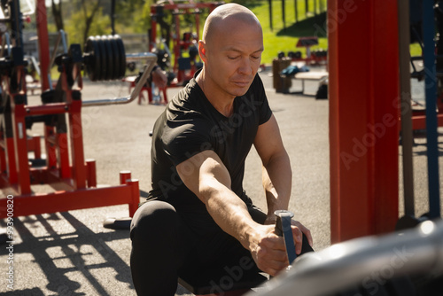 Lat rowing exercises. Adult man training at public gym park. Outdoors activity. Fitness coach show exercise for back. photo