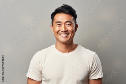 Portrait of a smiling asian man in his 40s donning a trendy cropped top in minimalist or empty room background