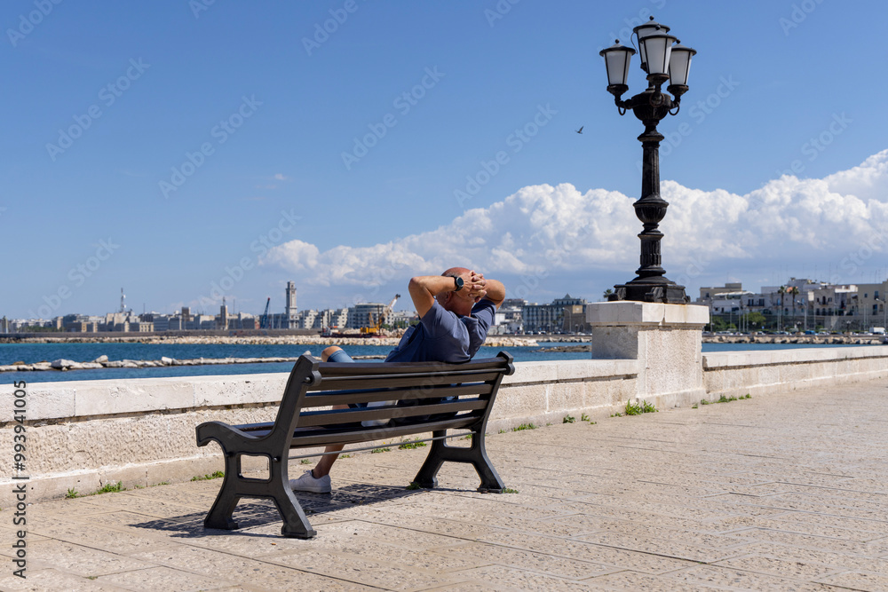 Man resting on a bench at Emperor Augustus seafront (Lungomare Imperatore Augusto), promenade by Adriatic Sea, Bari, Italy, Apulia