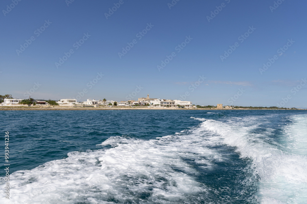 Polignano a Mare, Italy, Apulia - May 24, 2024: Picturesque view from the boat of the Adriatic Sea with a wake and the coast with Abbey of San Vito in the distance