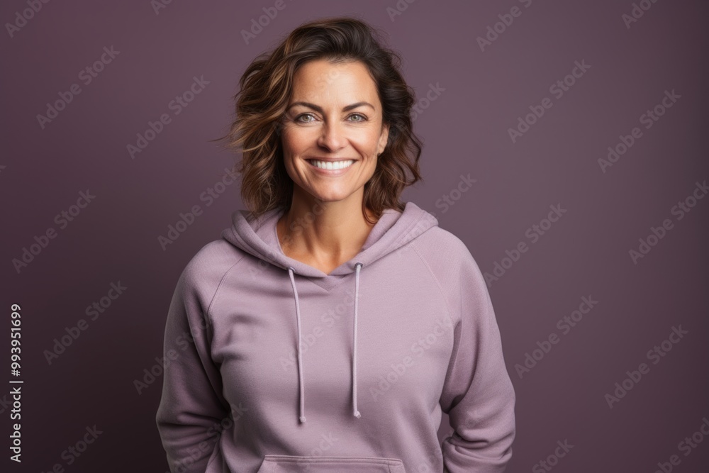 Fototapeta premium Portrait of a grinning woman in her 40s dressed in a comfy fleece pullover while standing against solid color backdrop