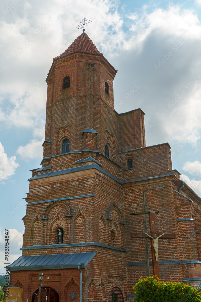 Fototapeta premium The Catholic church. The old red brick church. A historical building with a religious purpose.