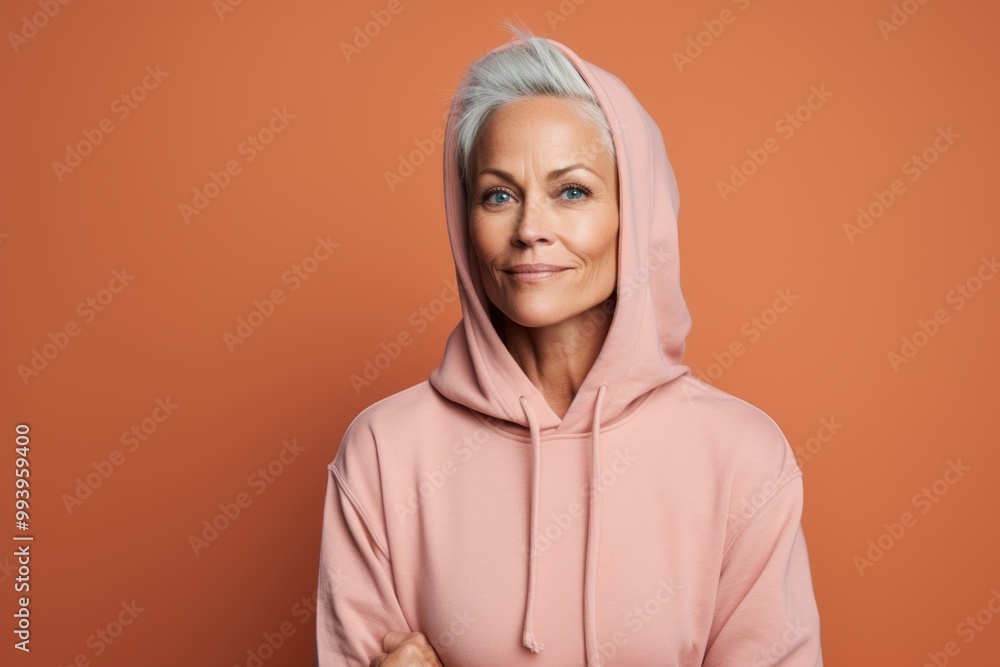 Portrait of a glad woman in her 50s wearing a zip-up fleece hoodie isolated in solid color backdrop Portrait of a glad woman in her 50s wearing a zip-up fleece hoodie isolated in solid color backdrop