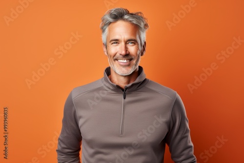 Portrait of a glad man in his 50s wearing a thermal fleece pullover on solid color backdrop