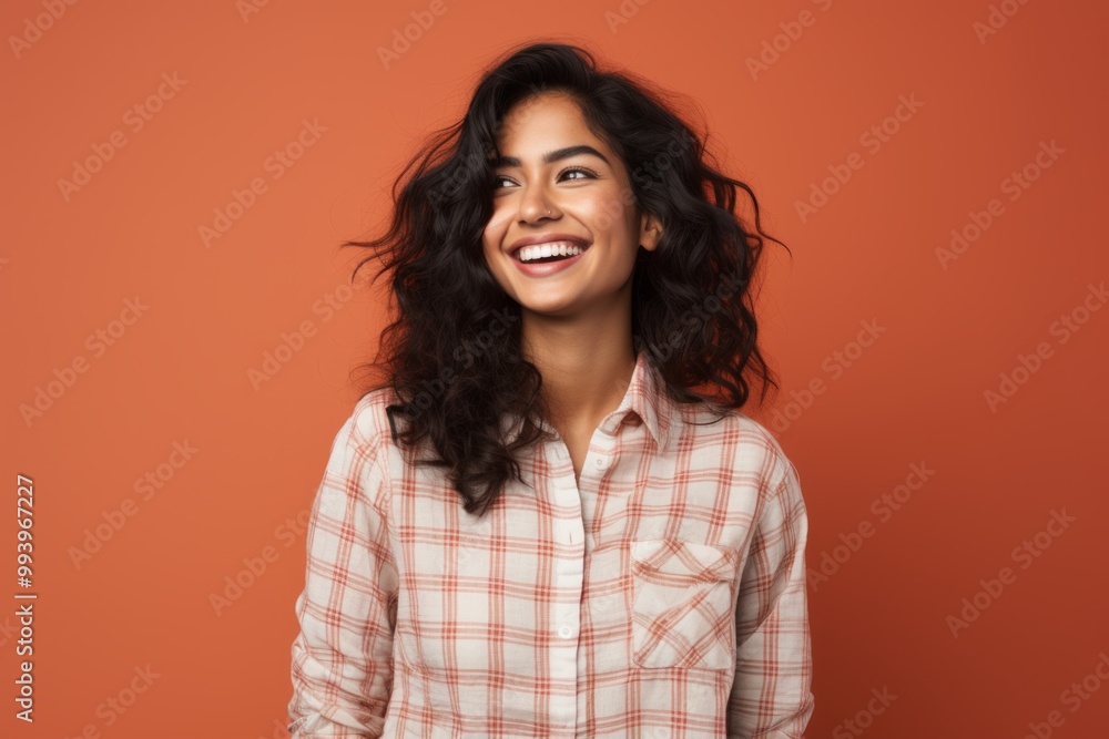 Portrait of a happy indian woman in her 20s dressed in a relaxed flannel shirt in front of solid color backdrop Portrait of a happy indian woman in her 20s dressed in a relaxed flannel shirt in front of solid color backdrop