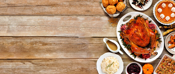 Thanksgiving turkey dinner. Above view side border on a rustic wood table banner background. Turkey, mashed potatoes, stuffing, pumpkin pie and sides.