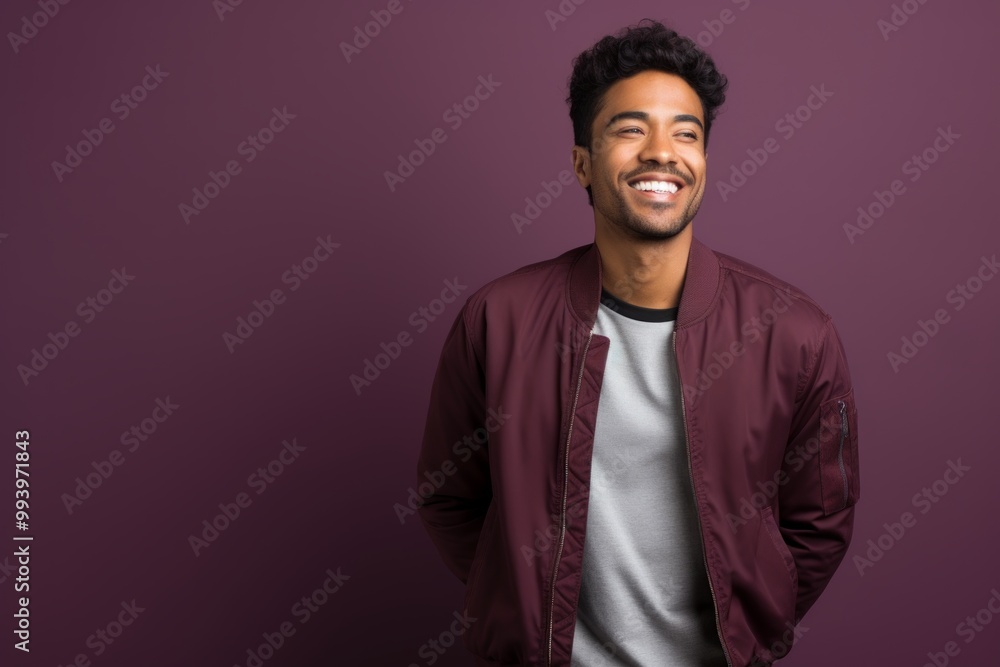 Portrait of a satisfied indian man in his 20s wearing a trendy bomber jacket over solid color backdrop Portrait of a satisfied indian man in his 20s wearing a trendy bomber jacket over solid color backdrop