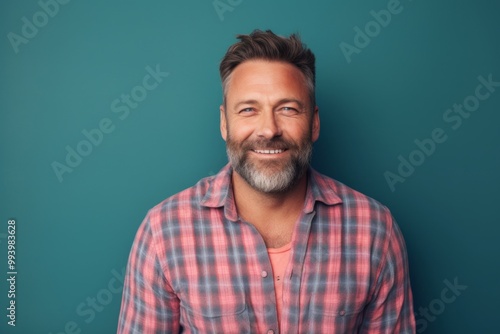 Portrait of a grinning man in his 40s wearing a comfy flannel shirt isolated on solid pastel color wall