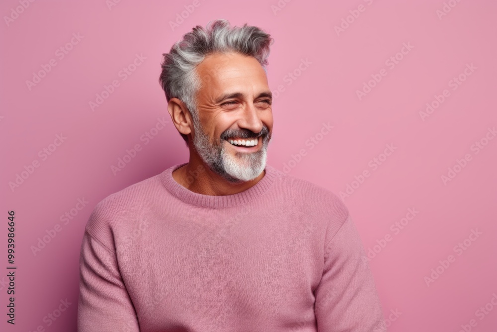 Portrait of a joyful man in his 50s wearing a cozy sweater in front of solid pastel color wall Portrait of a joyful man in his 50s wearing a cozy sweater in front of solid pastel color wall