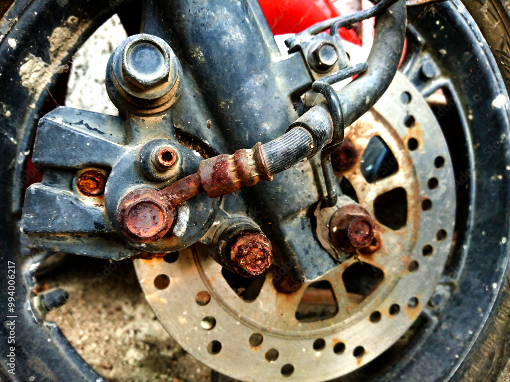 the front brake part of the motorbike is starting to rust. some bolts on the brake part are rusty and corroded. closeup for part motorcycle front brake, motorcycle front disc the front brake part of the motorbike is starting to rust. some bolts on the brake part are rusty and corroded. closeup for part motorcycle front brake, motorcycle front disc