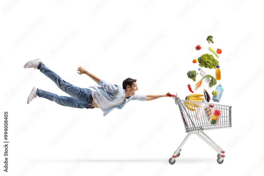 © Ljupco Smokovski - Full length shot of a casual guy man flying and holding a shopping cart with products falling © Ljupco Smokovski - Full length shot of a casual guy man flying and holding a shopping cart with products falling