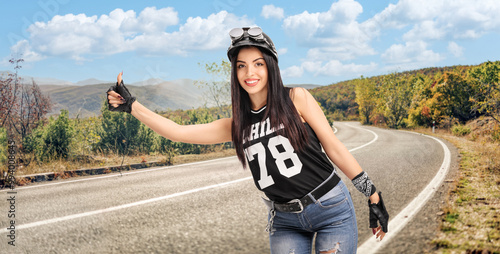 Young female biker hitchhiking with her thumb photo