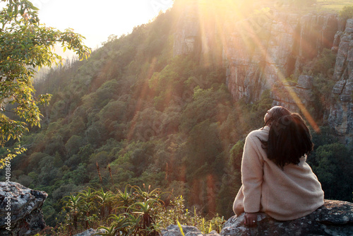 black African woman hiker on top of a mountain with sunset or sunrise in the background