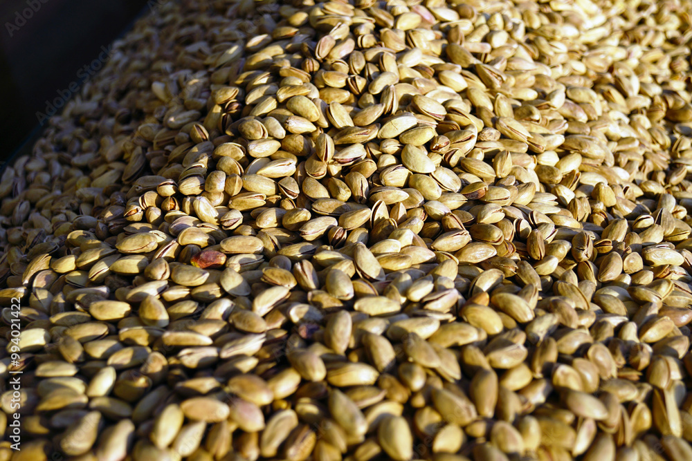 Obraz premium A large number of dried pistachios photographed close-up on a street stall in a Turkish market. The nuts are sold at a bazaar in the city of Gaziantep, known as the center of pistachio cultivation.