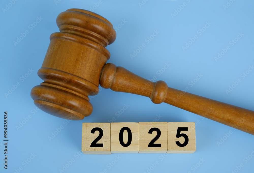 Wooden judge gavel and numbers 2025 on wooden cubes on blue background. Concept of laws in year 2025. Wooden judge gavel and numbers 2025 on wooden cubes on blue background. Concept of laws in year 2025.