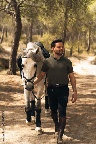 Happy man leads his horse on foot along an equestrian route on a sunny day. Concept of animal care. Vertical photo