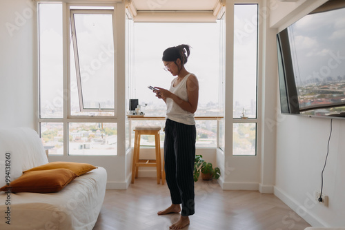 Asian woman walking around her room and chat with the mobile phone.