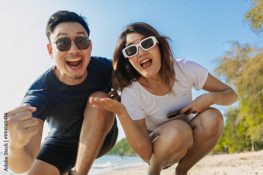 Playful asian couple lovers taking photo together at the beach, low angle. Playful asian couple lovers taking photo together at the beach, low angle.