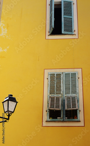 old window with shutters on ywllow walled building, france