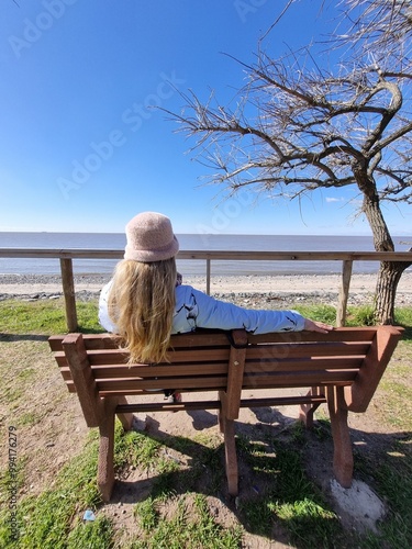Woman Relaxing on a Bench by the Seaside on a Sunny Winter Day