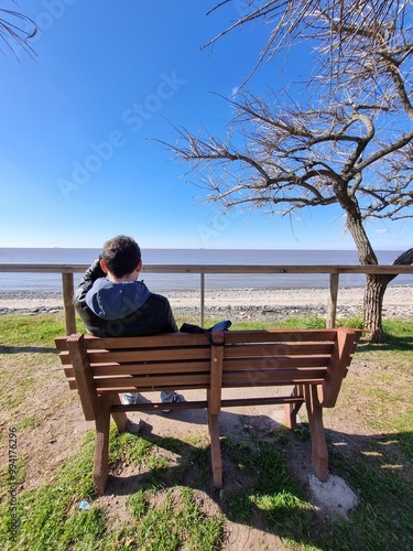 Man Sitting on a Bench by the Sea on a Sunny Day