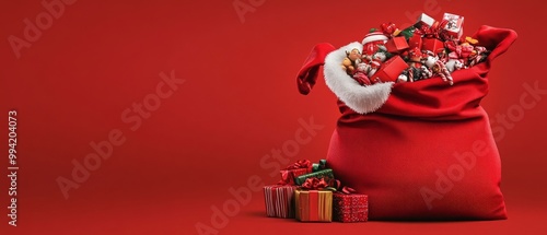 A red bag with a white santa hat on it is filled with many presents