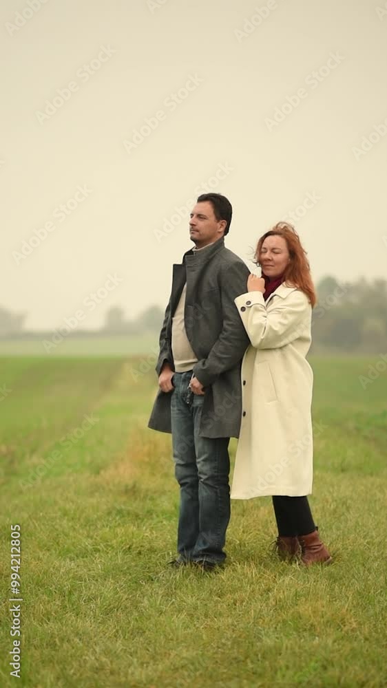 A young couple in autumn coats, nature, bad weather, rain, wind, a girl behind a man, looking into the distance, cinematography a love story. Relationships, family story A young couple in autumn coats, nature, bad weather, rain, wind, a girl behind a man, looking into the distance, cinematography a love story. Relationships, family story