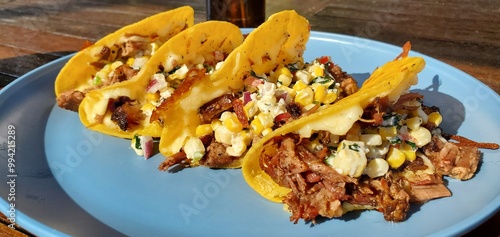 Delicious smoked brisket tacos topped with fresh corn and herb salsa, served on a sunny day for a perfect outdoor meal.