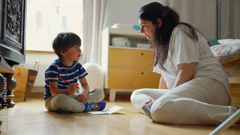Mother and son sitting on the floor, deeply involved in a creative project with colored pencils, enjoying quality time together in a bright, cheerful home setting Mother and son sitting on the floor, deeply involved in a creative project with colored pencils, enjoying quality time together in a bright, cheerful home setting