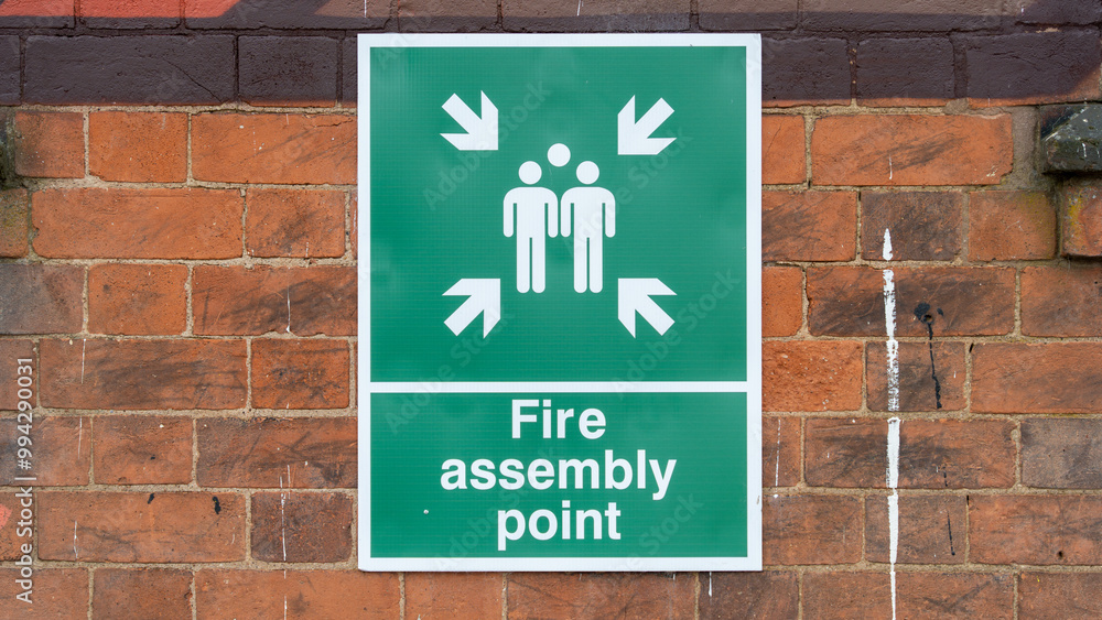 Fototapeta premium Fire Assembly Point Sign Mounted on a Brick Wall