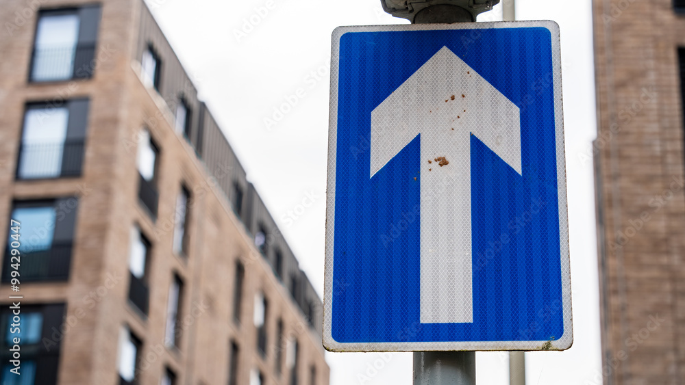 Blue One-Way Traffic Sign with Urban Building Background Blue One-Way Traffic Sign with Urban Building Background