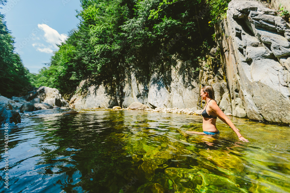 Blonde woman in bikini swimming and relaxing in a clear water river with rock cliffs and free stones. Clarendon Gorge, Vermont, New England, USA. Blonde woman in bikini swimming and relaxing in a clear water river with rock cliffs and free stones. Clarendon Gorge, Vermont, New England, USA.