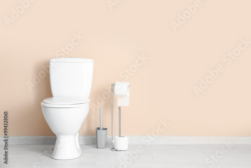 Holder with rolls of paper, ceramic toilet bowl and brush near color wall