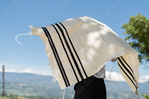 Fotografi Young Jewish Man Draping the Tallit Over His Body Outdoors Under Blue Sky