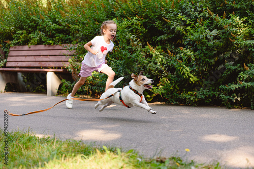 The dog got loose off its leash and runs away from young owner in park. photo