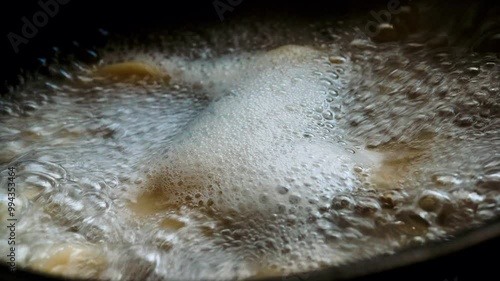 Ravioli boiling in water. Water boils in a saucepan. Boiling water foams. Dumplings are cooked in sauce. Hot water bubbles on the fire in the kitchen. Delicious food is being prepared. Cook food
