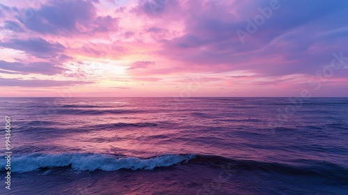 The ocean is calm and the sky is a beautiful shade of pink. The water is a deep blue color